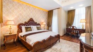 ein großes Schlafzimmer mit einem großen Bett und zwei Tischen in der Unterkunft GREGORY Boutique Hotel Chisinau in Chişinău