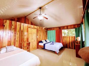 The Sunset Tucano Lodge في دريك: غرفة نوم بسريرين ومروحة سقف