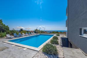 a swimming pool in a yard with chairs and a building at Villa Apartments AniFil in Novalja