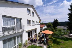 a person sitting under an umbrella outside of a building at Hotel an der Sonne in Schönwald