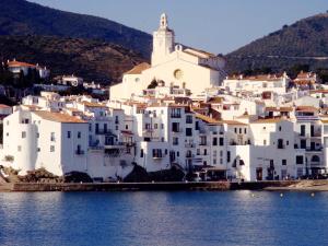 un grupo de edificios blancos en una colina junto al agua en Très bel appartement (40m²) avec piscine privative, en Perpiñán