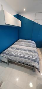 una cama en una habitación con una pared azul en Studio Apartment between Nice and Cannes - Marina baie des Anges - Beach, restaurants, shops - tea/coffee/sugar/bed linen and towels, en Villeneuve-Loubet