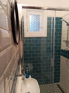 La salle de bains est pourvue de carrelage vert, d'un lavabo et d'une fenêtre. dans l'établissement Nárcisz Vendégház, à Mezőkövesd