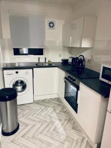 a kitchen with white cabinets and a washing machine at Modern 2 Bedroom Apartment With Free Parking in Glasgow