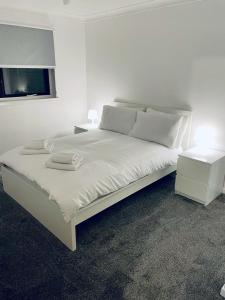 a white bedroom with a large white bed with a window at Modern 2 Bedroom Apartment With Free Parking in Glasgow