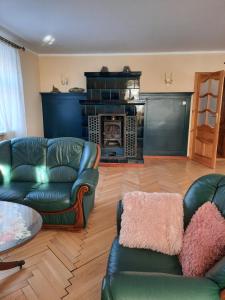 a living room with leather couches and a fireplace at Dworek nad Potokiem in Karpacz