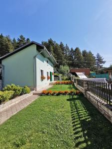 a house with a fence and a yard with flowers at Ubytovanie v súkromí Zelený dom in Vyšné Ružbachy