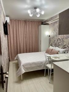 a bedroom with a bed and a table and a kitchen at Уютная комната-студия в центре Бишкека in Bishkek