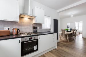 a kitchen with white cabinets and a stove top oven at Clayton House - Spacious home near Etihad Stadium in Manchester