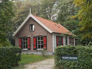 een klein huis met rode luiken en een bord bij Hotel Gaia in Diepenveen