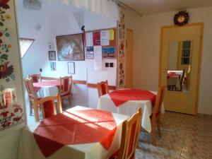 a dining room with two tables and chairs with red covers at Agria Retur Vendégház in Eger