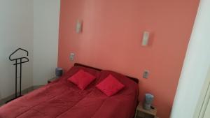 een rood bed met twee rode kussens in een slaapkamer bij Appartement cure ou vacances avec WIFI et parking et à 100m des thermes in Amélie-les-Bains-Palalda