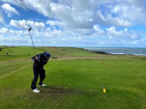 a man swinging a golf club on a golf course at 2 Bedroom Family Cottage Dog Friendly Edern North Wales in Ederyn
