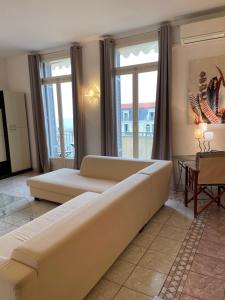 a living room with a large couch and windows at Menton centre Vue imprenable sur mer et jardin Biovès in Menton