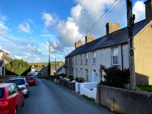 une rue avec des voitures garées sur le côté d'une maison dans l'établissement 2 Bed Cottage Dog Child Friendly 15min walk to beach, à Ederyn