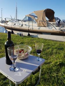 a table with two glasses and a bottle of wine and a boat at Het Schiphuis met privé haven in Heeg