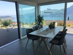 Krattigen的住宿－Moderne Unterkunft mit Panoramablick auf Thunersee，一间带桌椅和大窗户的用餐室