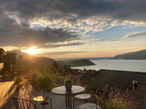 um pôr-do-sol numa varanda com uma mesa e cadeiras em Moderne Unterkunft mit Panoramablick auf Thunersee em Krattigen