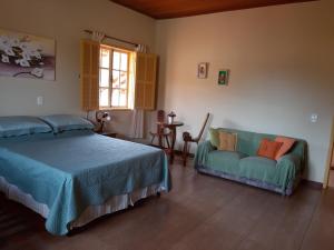 1 dormitorio con cama, sofá y ventana en Pousada As Relíquias de Minas, en Tiradentes