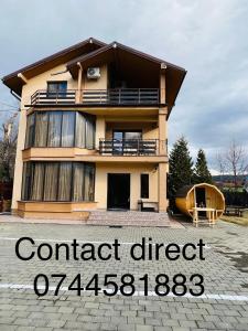 a house with a sign that reads contact direct at Pensiunea Ianis Piatra Neamt in Piatra Neamţ
