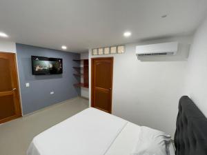 um quarto com uma cama e uma televisão na parede em Hotel Aeromar Central em Santa Marta