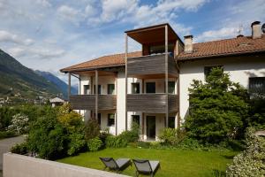 a large house with two chairs in the yard at Apartments Schwarzlehen in Naturno