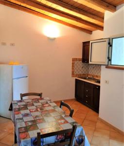 eine Küche mit einem Tisch und einem weißen Kühlschrank in der Unterkunft LE VILLETTE DI TERRANOVA in Lampedusa