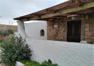 ein Gebäude mit einem Holzdach und einer Wand in der Unterkunft LE VILLETTE DI TERRANOVA in Lampedusa