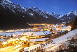 a town in the snow at night with mountains at Haus Wohleb in Fulpmes