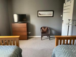 a bedroom with a tv and a chair and a dresser at The Number Eleven Apartment in Kilmuir