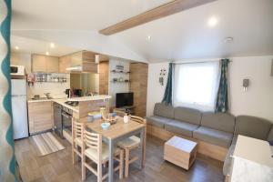 uma cozinha e sala de estar com uma mesa e um sofá em Mobil Home 8 personnes em Les Mathes