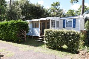 une petite maison dans une cour avec des buissons dans l'établissement Mobil Home 8 personnes, aux Mathes