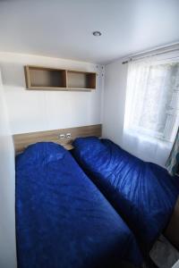 een slaapkamer met een blauw bed en een raam bij Mobil Home 8 personnes in Les Mathes