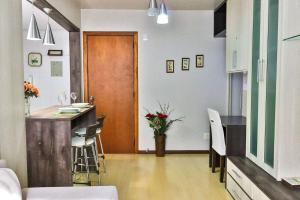 a room with a kitchen and a table with a vase of flowers at LOCAR-IN GRAMADO - Residencial Benetti in Gramado