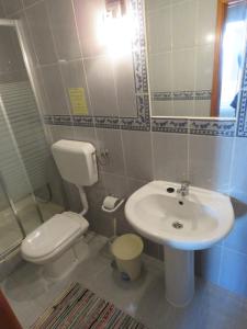 La salle de bains est pourvue de toilettes blanches et d'un lavabo. dans l'établissement Casa do Quintalão, à Raposeira