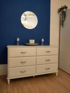 a dresser with a mirror on a blue wall at Cheerful Gem of Barking & Dagenham 3 Bedroom House Entire Property in Goodmayes