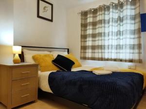 a bedroom with a bed with yellow pillows and a night stand at Cheerful Gem of Barking & Dagenham 3 Bedroom House Entire Property in Goodmayes