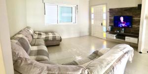 uma sala de estar com um sofá e uma televisão em Casa em Capao em Capão da Canoa