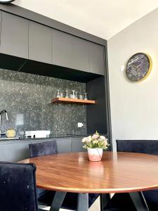 エイラットにあるEsterin Royal Park Apartments Eilatのダイニングテーブルと椅子、そして壁に掛けられた時計