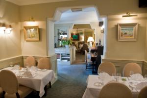 um restaurante com mesas e cadeiras brancas e uma sala de jantar em Aherne's Townhouse Hotel and Seafood Restaurant em Youghal