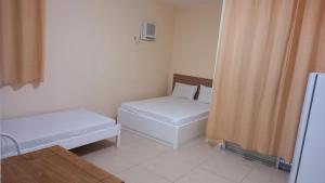 a small room with two beds and a window at Atlantica Suites in Guarujá +3 photos