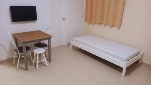 a small room with a bed and a table and a desk at Atlantica Suites in Guarujá