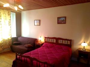 um quarto com uma cama vermelha e um sofá em Chez Maria em Charix