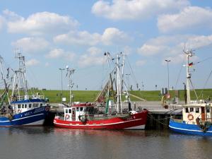 drei Boote, die an einem Dock im Wasser angedockt sind in der Unterkunft Doppelhaushälfte Friesenglück mit Sauna in Dornumersiel