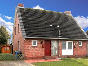 ein rotes Backsteinhaus mit einem schwarzen Dach in der Unterkunft Doppelhaushälfte Friesenglück mit Sauna in Dornumersiel + 4 Fotos
