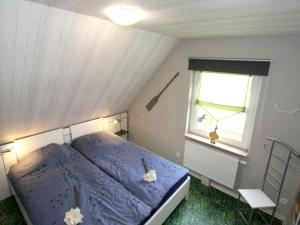 ein Schlafzimmer mit einem blauen Bett und einem Fenster in der Unterkunft Doppelhaushälfte Friesenglück mit Sauna in Dornumersiel