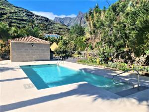 una piscina en un patio trasero con montañas al fondo en Haciendita Gomera, en San Sebastián de la Gomera