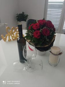 a table with a bottle of wine and a bouquet of red roses at Apartman Carpe Diem in Sutomišćica