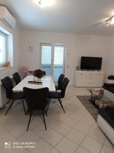 a living room with a table and chairs and a tv at Apartman Carpe Diem in Sutomišćica