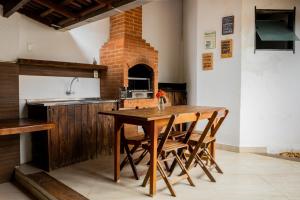 a kitchen with a wooden table and a brick oven at Pousada Buriti in Itaúnas